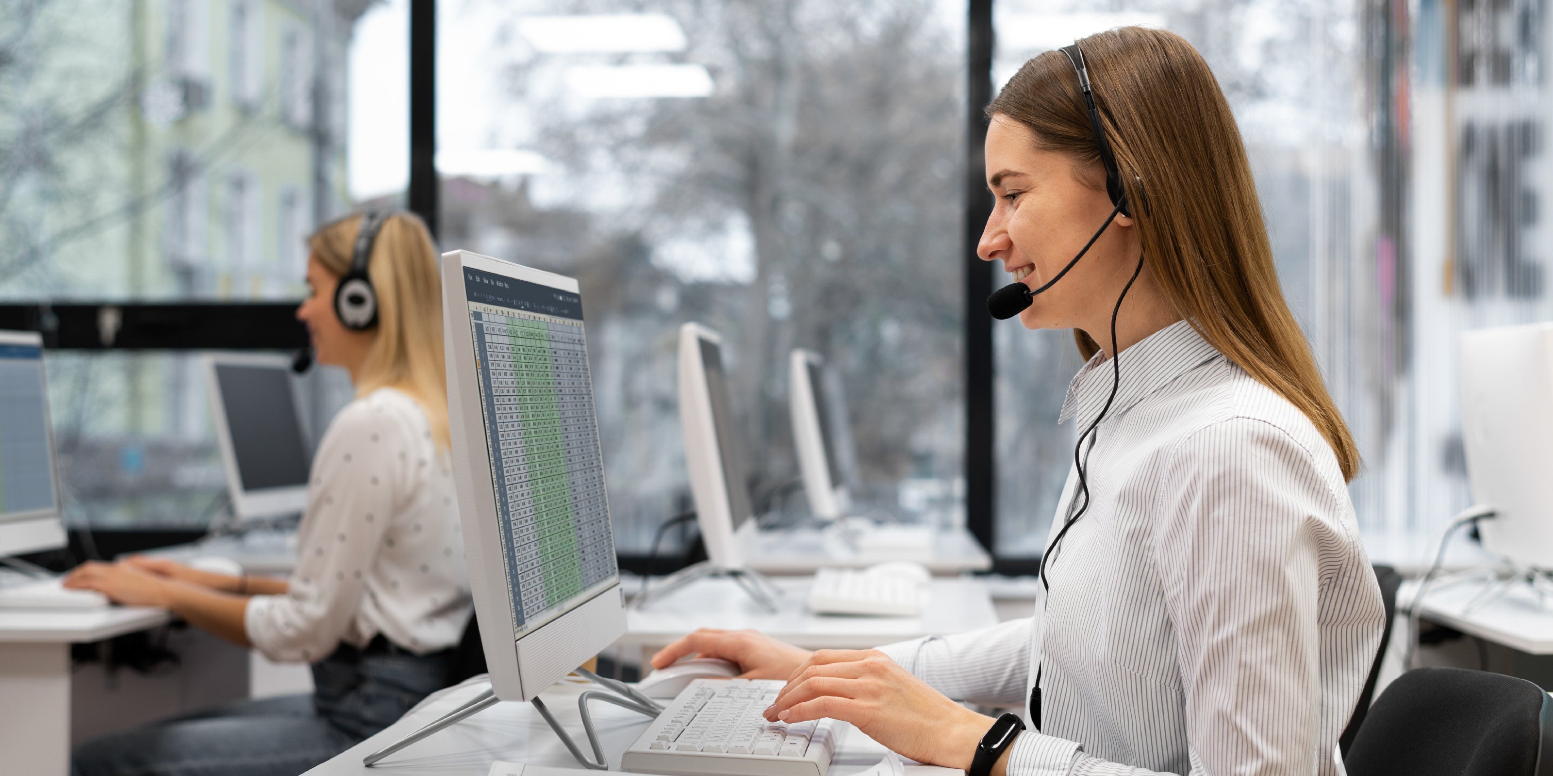 Call center agents working at their desks with computers and headsets.