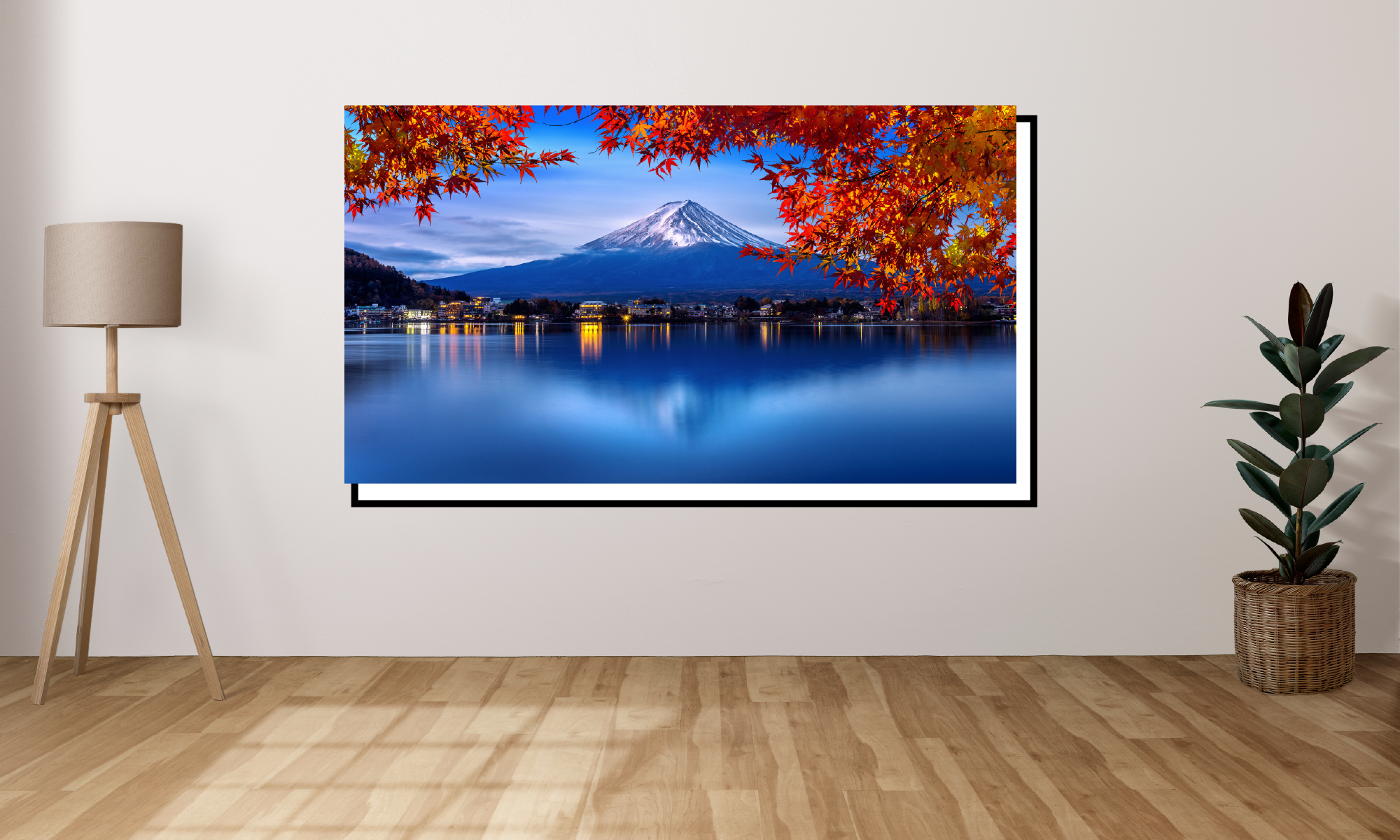 Framed artwork of a mountain landscape with autumn foliage in a room with a lamp and plant.